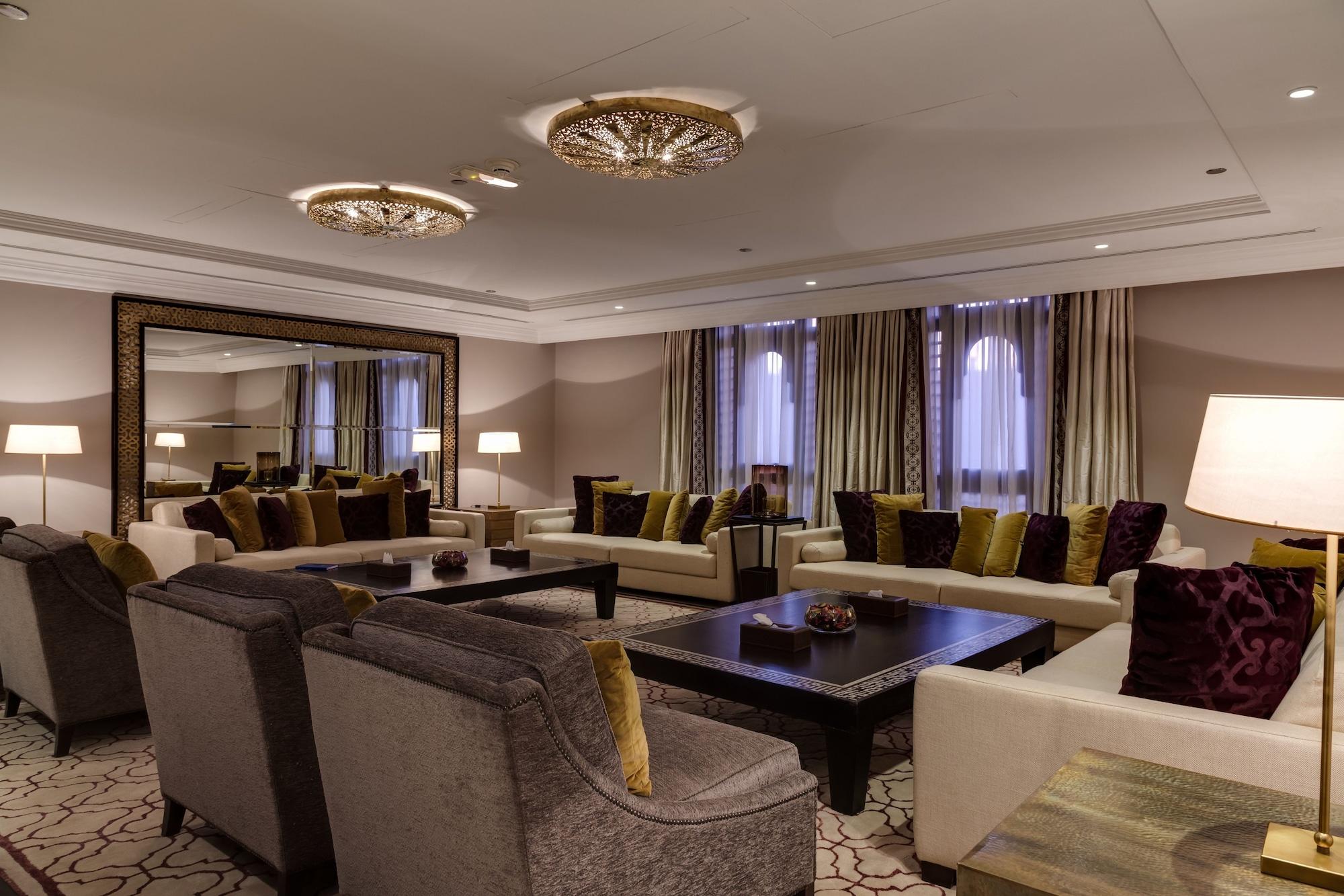فندق شهد المدينة بإدارة اكور المدينة المنورة المظهر الخارجي الصورة The photo showcases an elegant living room designed with a sophisticated aesthetic. It features a mix of plush seating arrangements, including gray sofas and armchairs adorned with colorful cushions in shades of green and purple. A large, dark coffee
