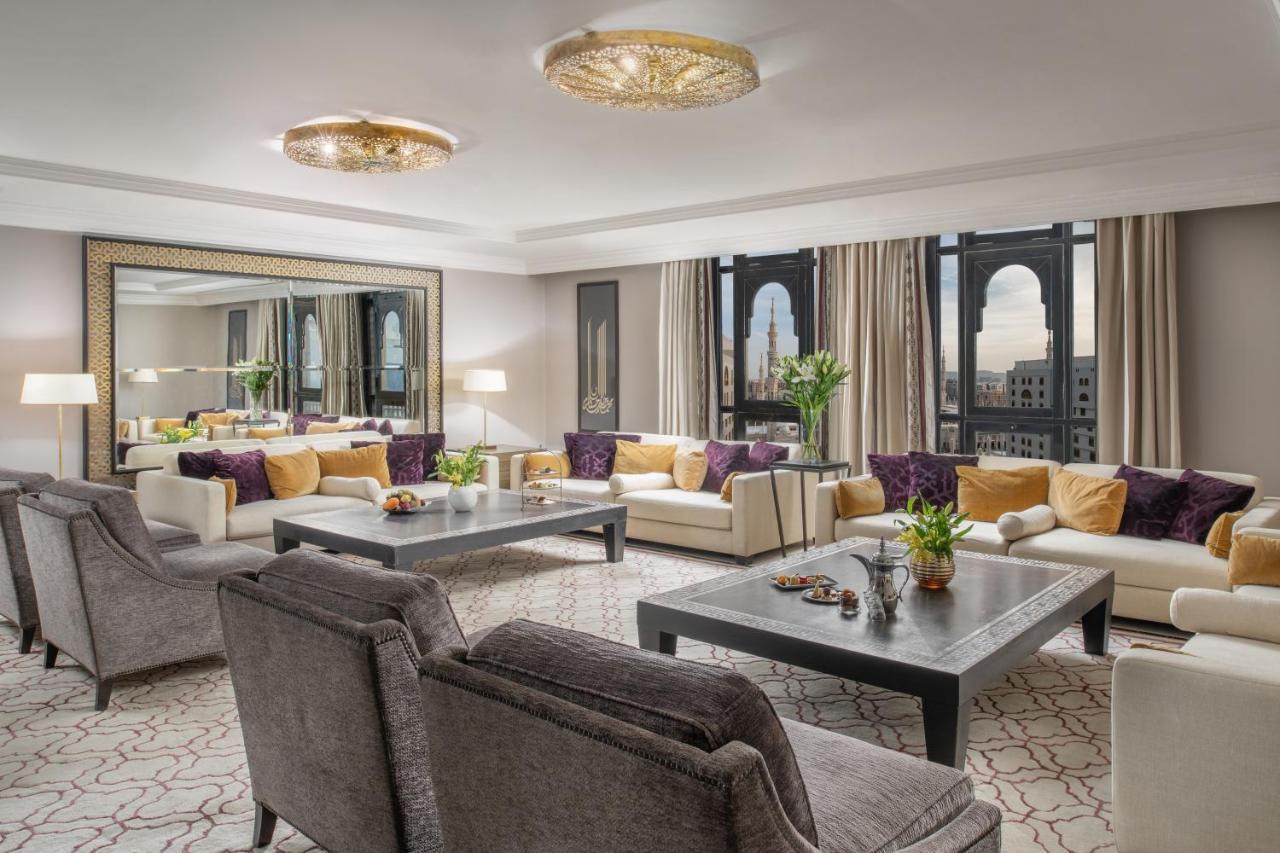 فندق شهد المدينة بإدارة اكور المدينة المنورة المظهر الخارجي الصورة The photo shows a luxurious living room space. It features elegant furniture, including plush sofas with a mix of light and dark tones, and decorative cushions. A large coffee table sits in the center, adorned with a small plant and decorative items.