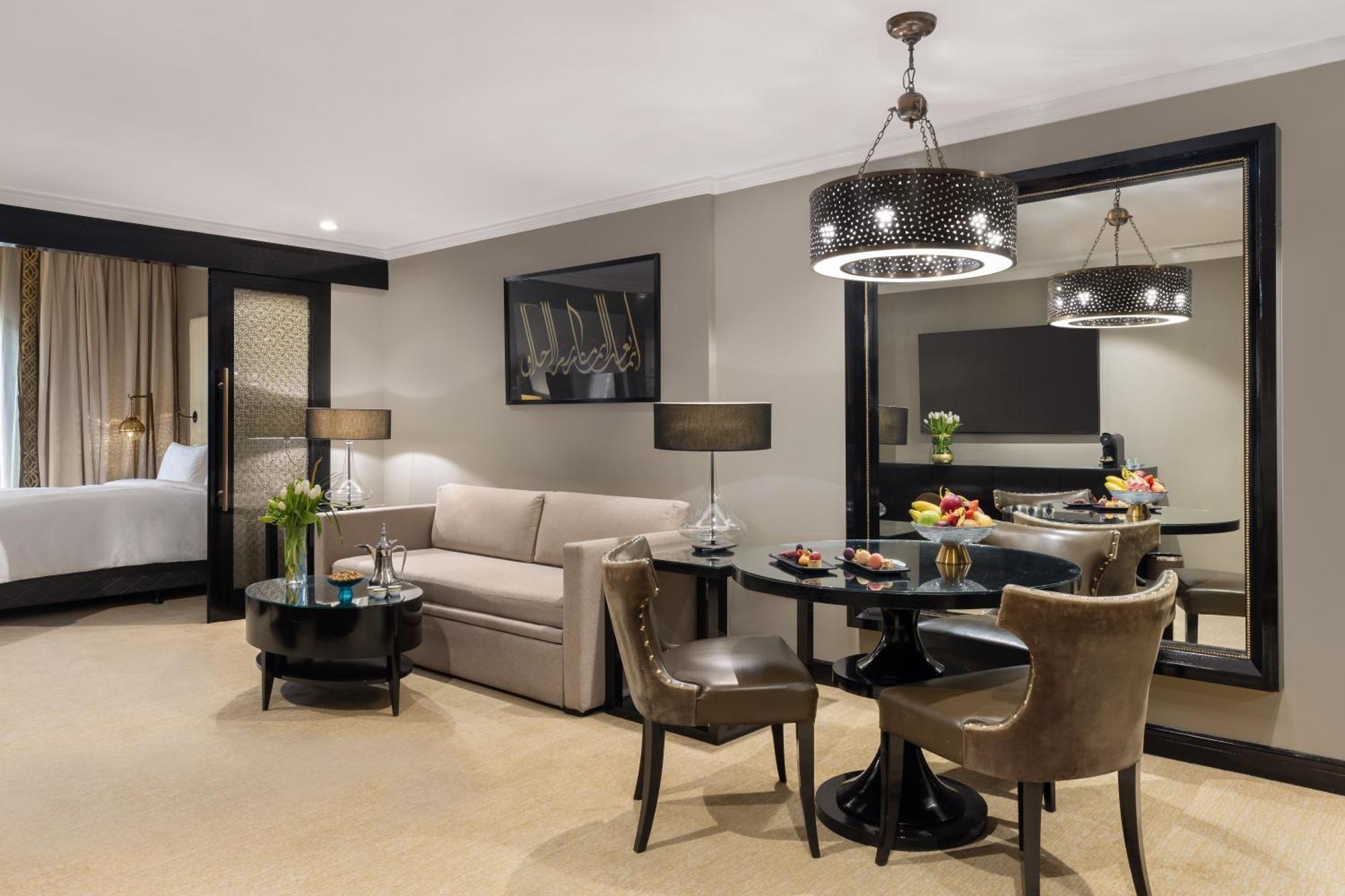 فندق شهد المدينة بإدارة اكور المدينة المنورة المظهر الخارجي الصورة The photo shows a stylish hotel or apartment room designed for comfort and elegance. 

- On the left, there's a light-colored sofa paired with a round coffee table.
- Adjacent to the sofa, there are two upholstered chairs, creating a cozy seating are